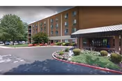 Brick senior living facility with a covered entrance, parking area, and manicured landscaping.