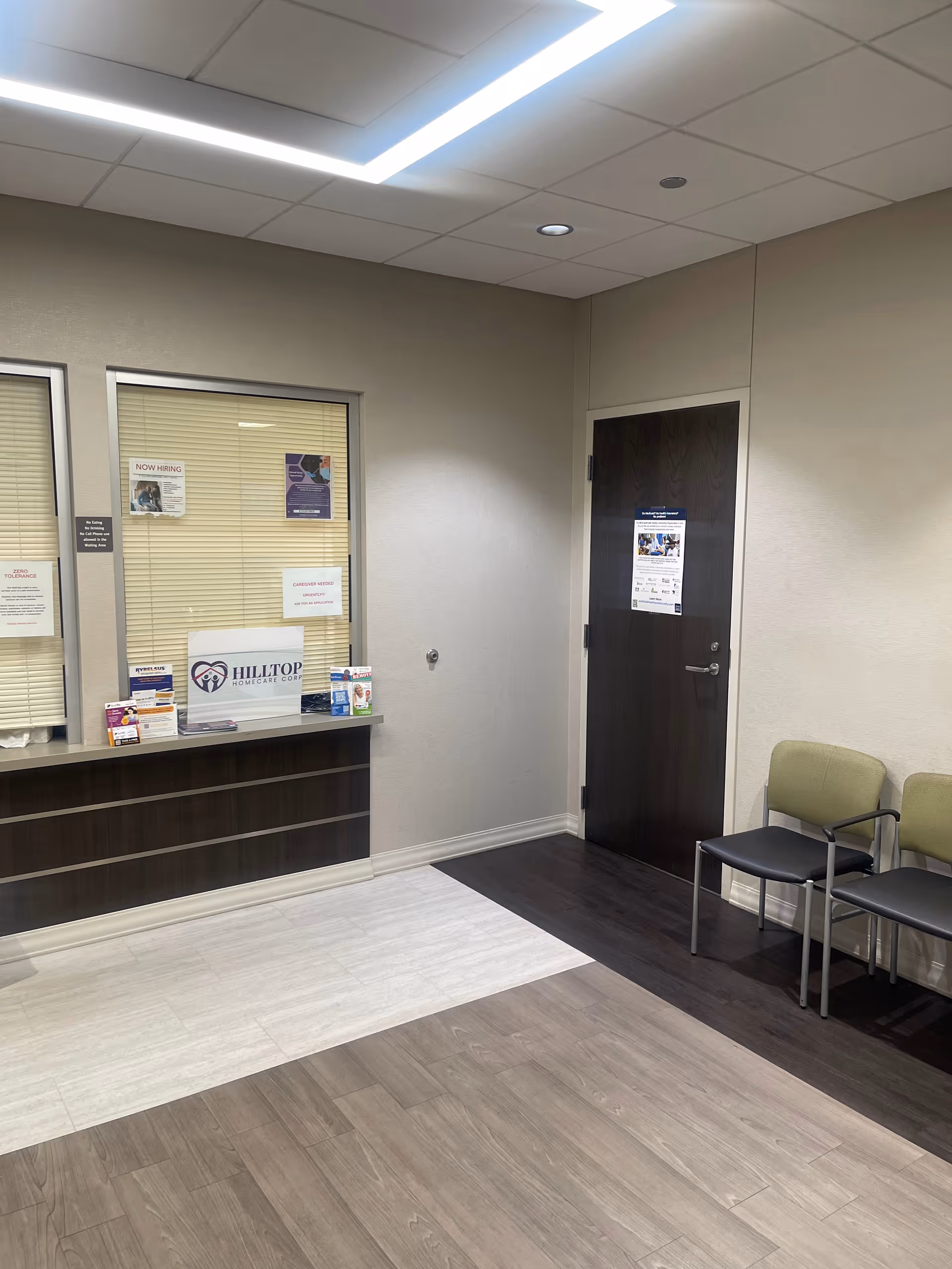 Hilltop Homecare Corp reception area with a desk, window blinds, posters, and waiting chairs.