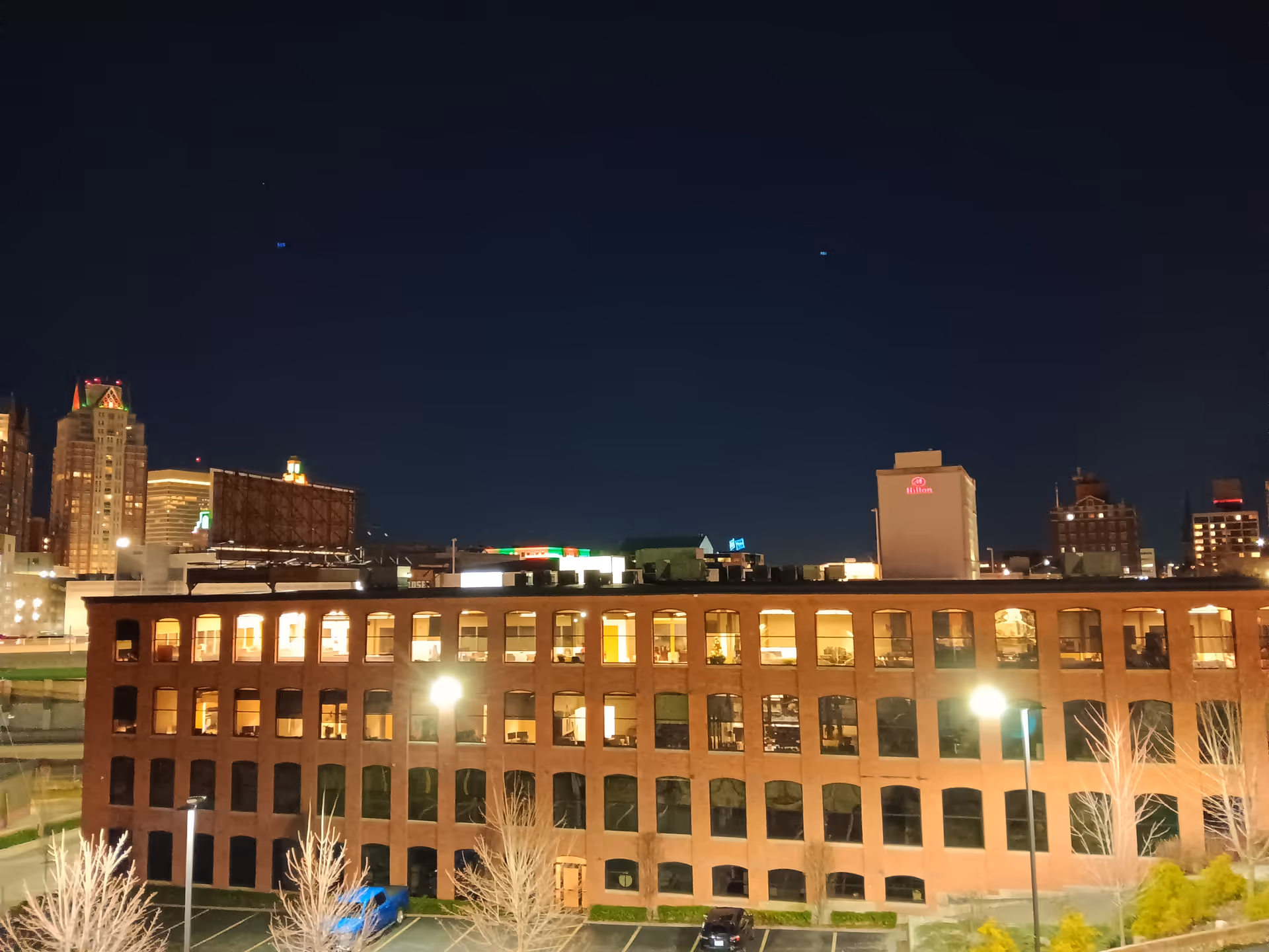 Nighttime city view featuring a brick building front with glowing office windows.