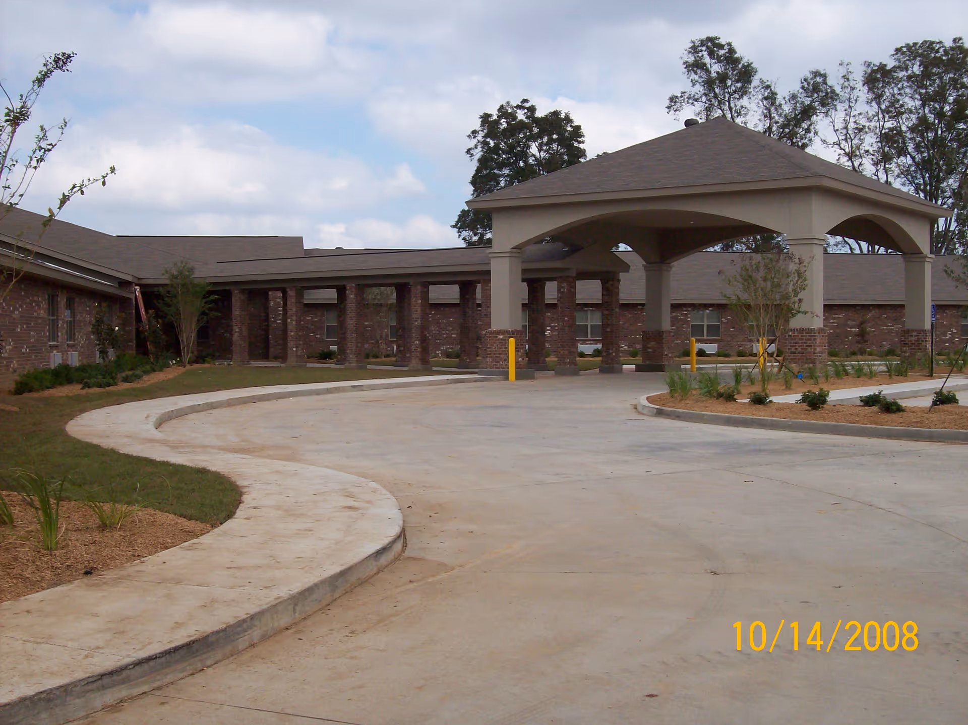Drive-up entrance with a covered porte-cochère in front of a single-story brick nursing facility.