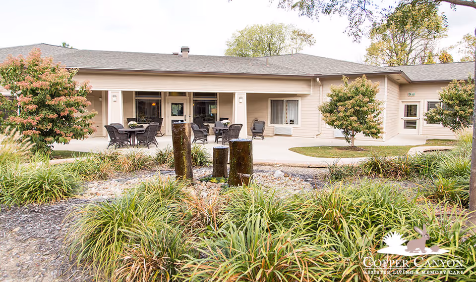 Exterior view of Copper Canyon facility with covered patio, tables, chairs, and landscaping.