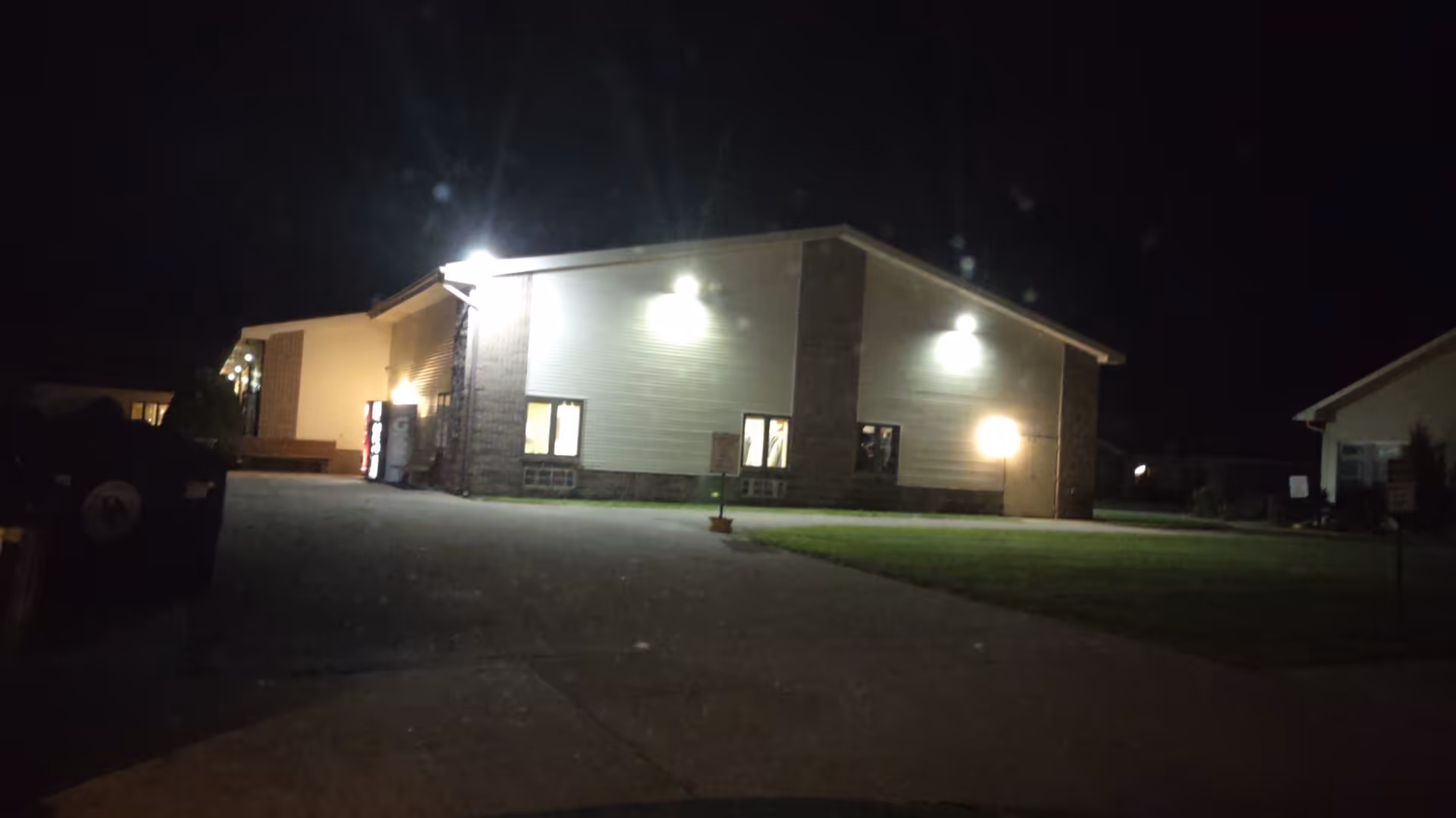 Night exterior view of Bishop Noa Home building with illuminated entrance and surrounding yard.