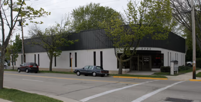 Exterior of Saving Grace facility along a tree-lined street.