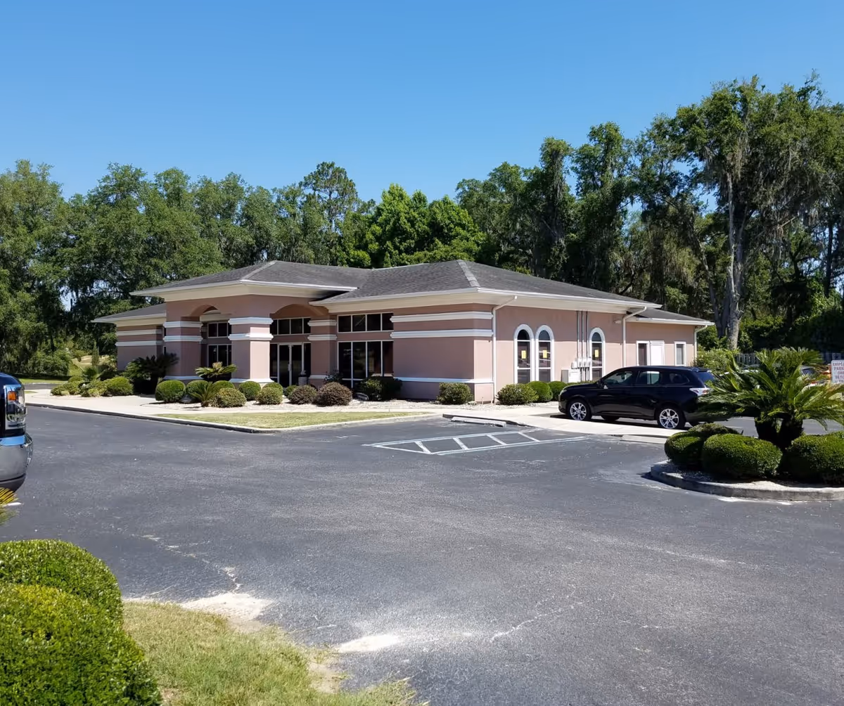 Front exterior of Brooks Rehabilitation Home Health Gainesville building with parked cars and trees.