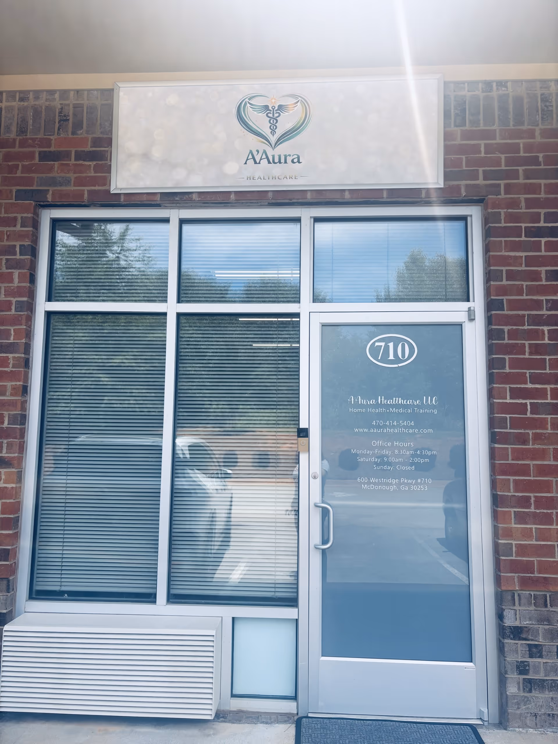 Exterior view of A'Aura Healthcare entrance with brick facade, glass door, and sign.