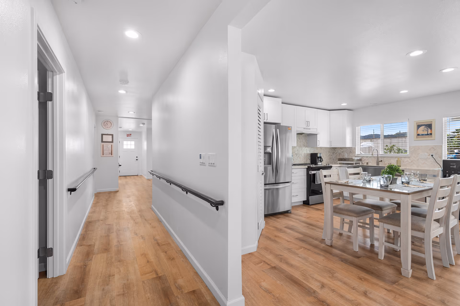 Bright hallway on left leads to a white kitchen and dining area with wooden floors.