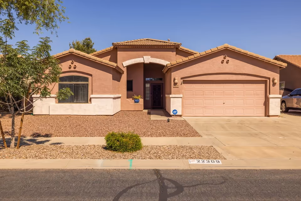 A single-story pink stucco senior living facility with a two-car garage and arched entrance.