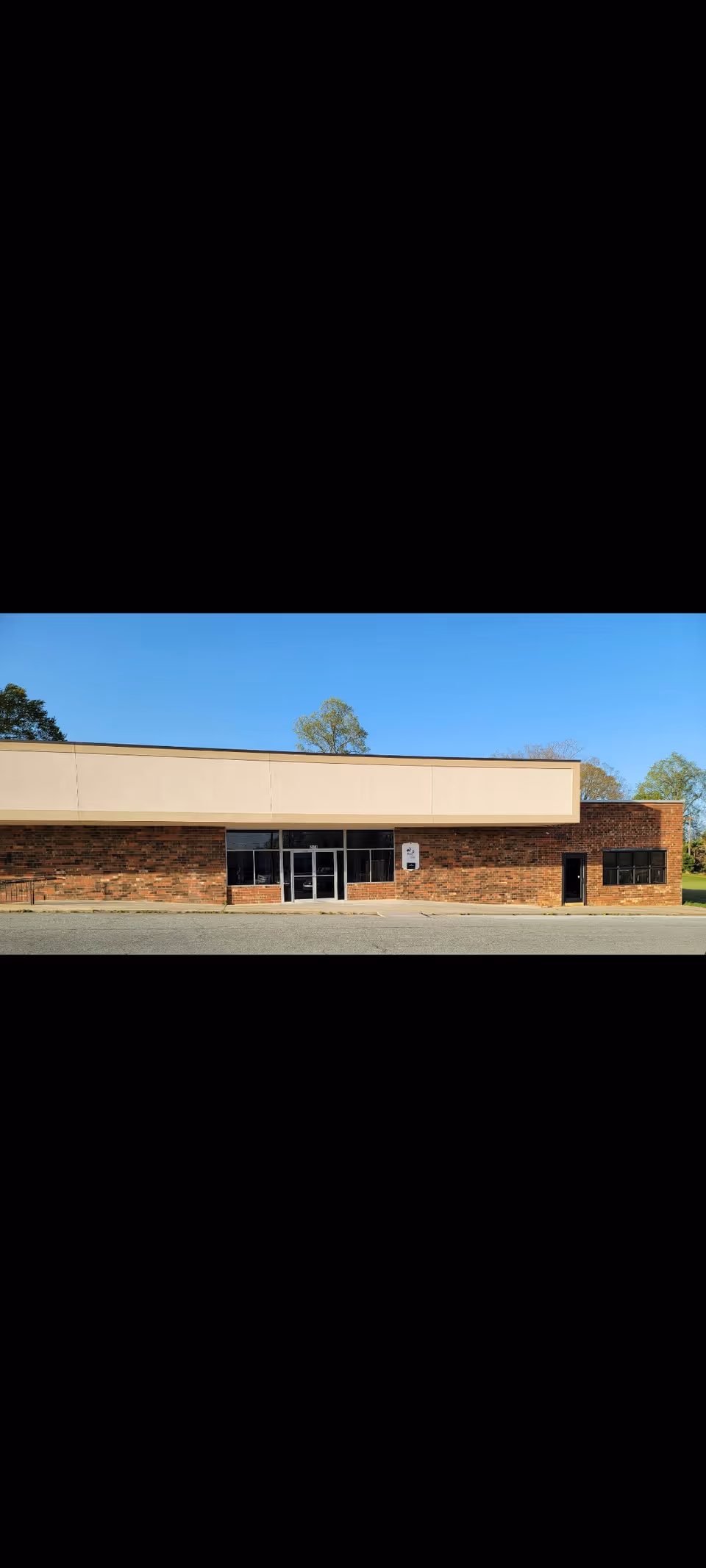 Front exterior of a brick and beige senior facility with glass doors.
