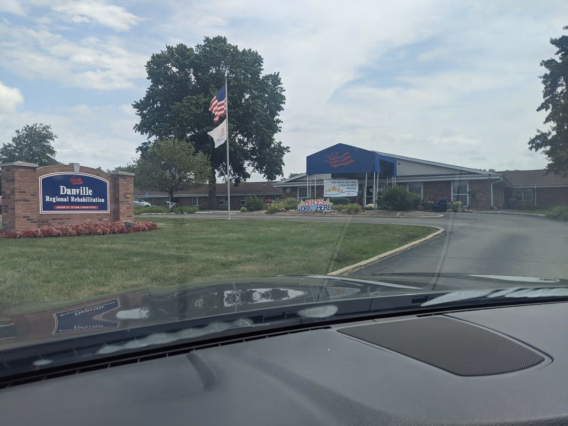 Front view of Danville Regional Rehabilitation building with sign, flagpoles, and blue entrance canopy.
