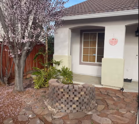Residential front entrance of Chenin Blanc Assisted Living with flowering tree and circular brick planter.