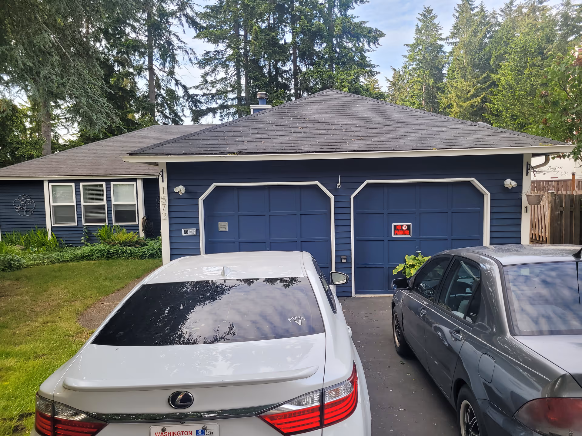 Blue single-story home with two garage doors and parked cars.