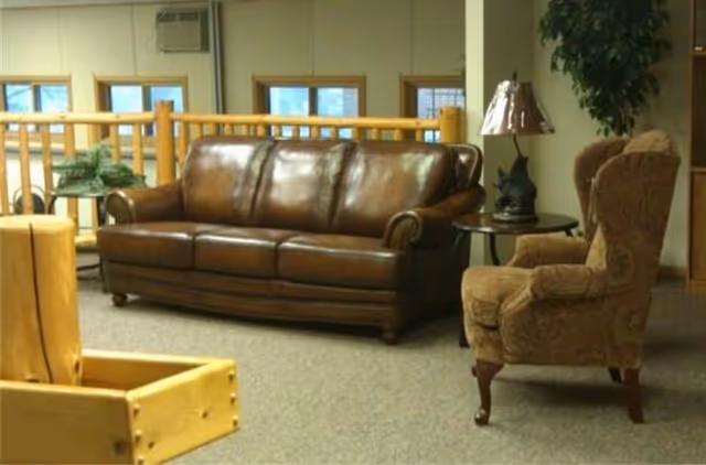 Cozy lounge in a senior living facility with brown leather sofa and chairs.