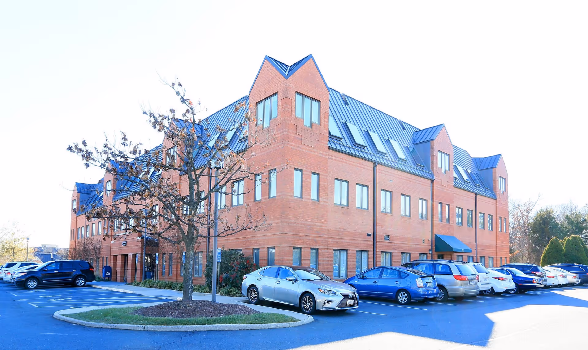 Brick senior living facility with many windows and a row of parked cars outside