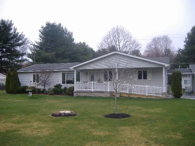 Front view of a single-story care facility with a porch and well-kept lawn.