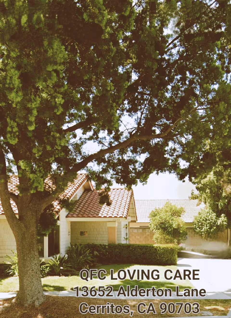 Exterior view of QFC Loving Care facility with trees and front entrance.
