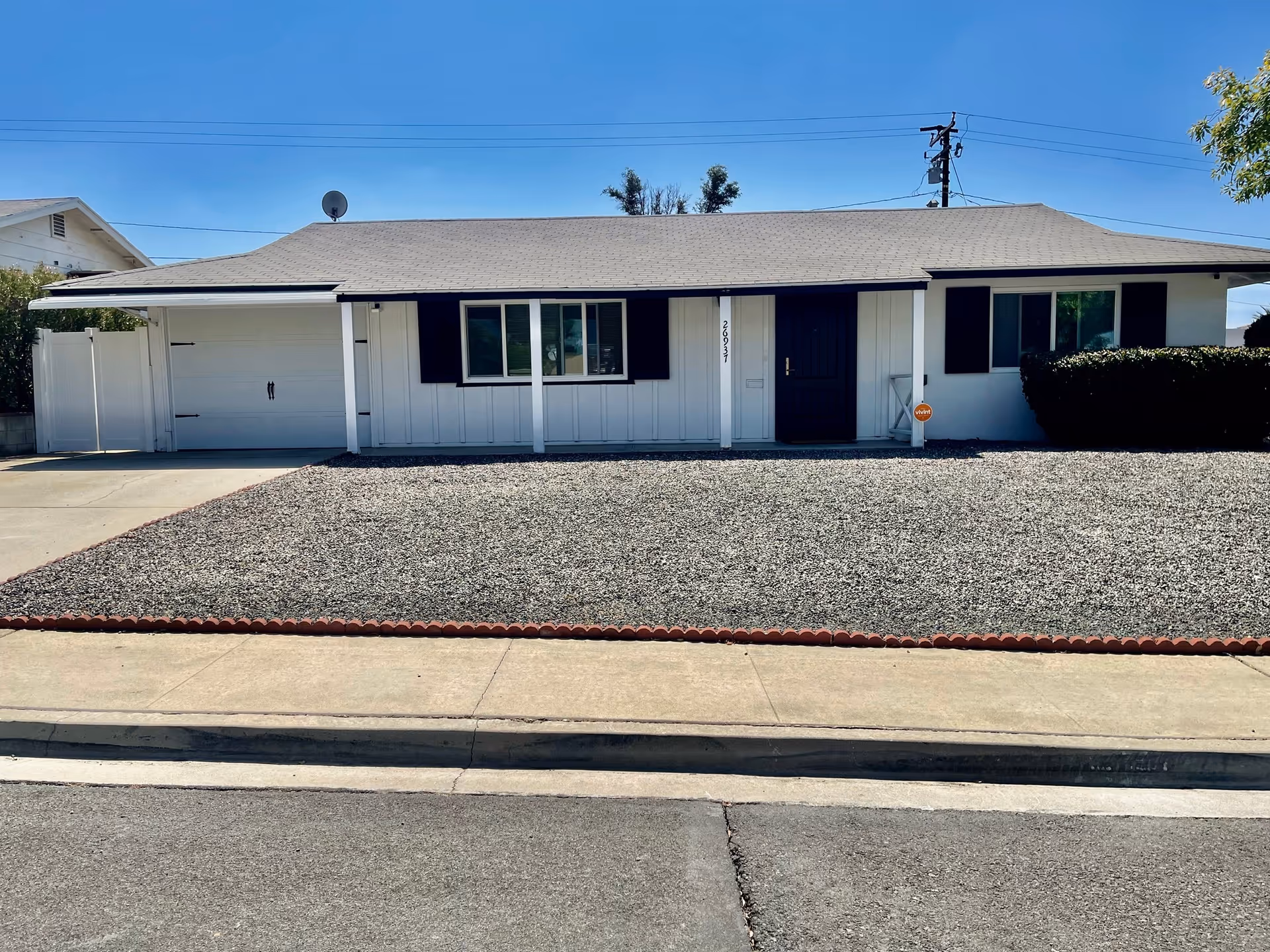 Single-story building facade with a gravel yard and front entrance visible.