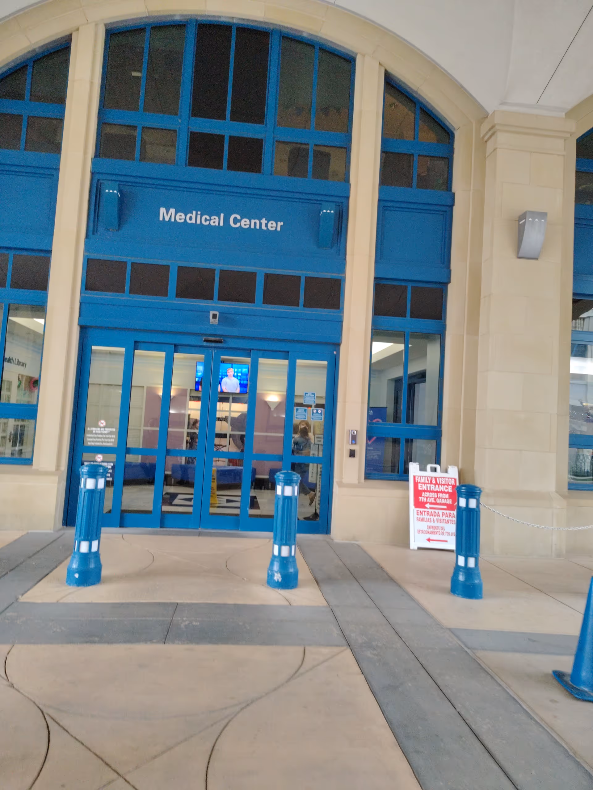 Blue framed glass doors reading Medical Center, exterior entrance with bollards and a sign.