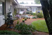 Outdoor courtyard with brick path, planters, and seating beside the facility.