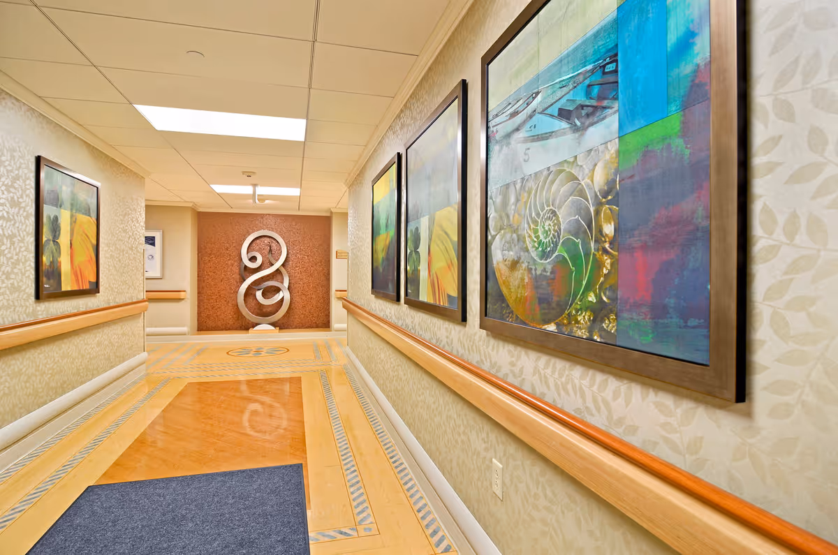 Long beige corridor with framed artwork and wooden handrails.