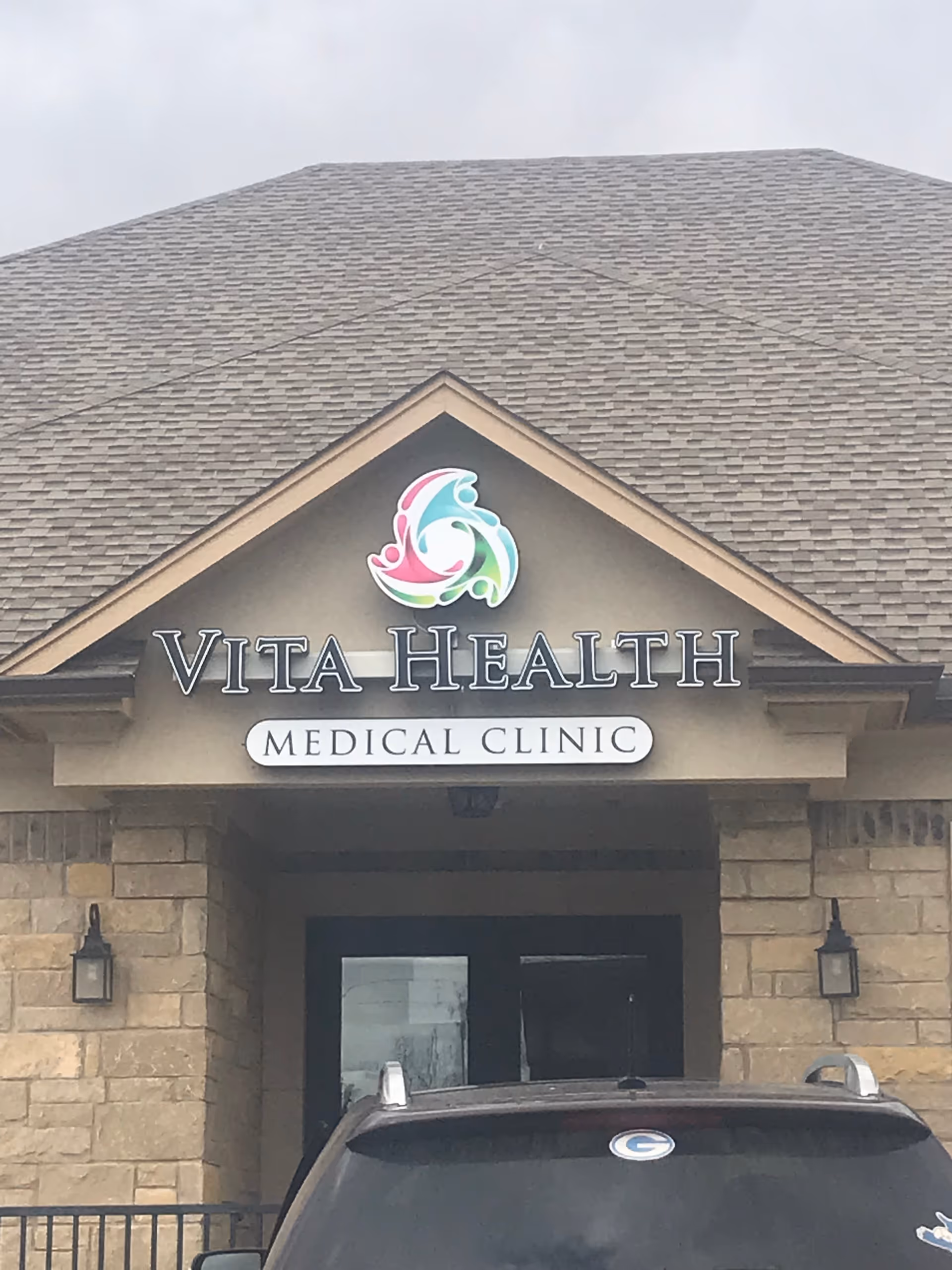 Front view of Vita Health Medical Clinic sign on stone building facade.