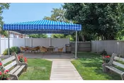 Outdoor courtyard with a blue striped canopy, picnic tables, and benches.