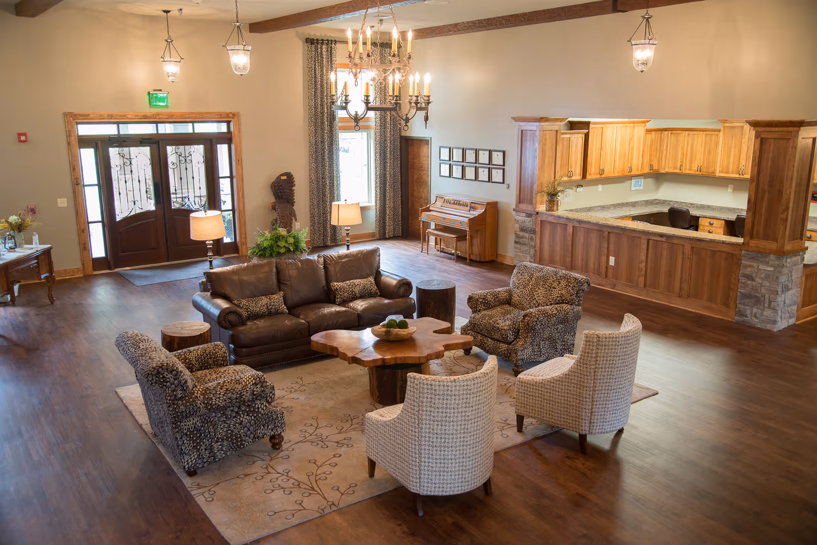 Spacious living room with sofas, chairs, rug, chandelier, and open kitchen.