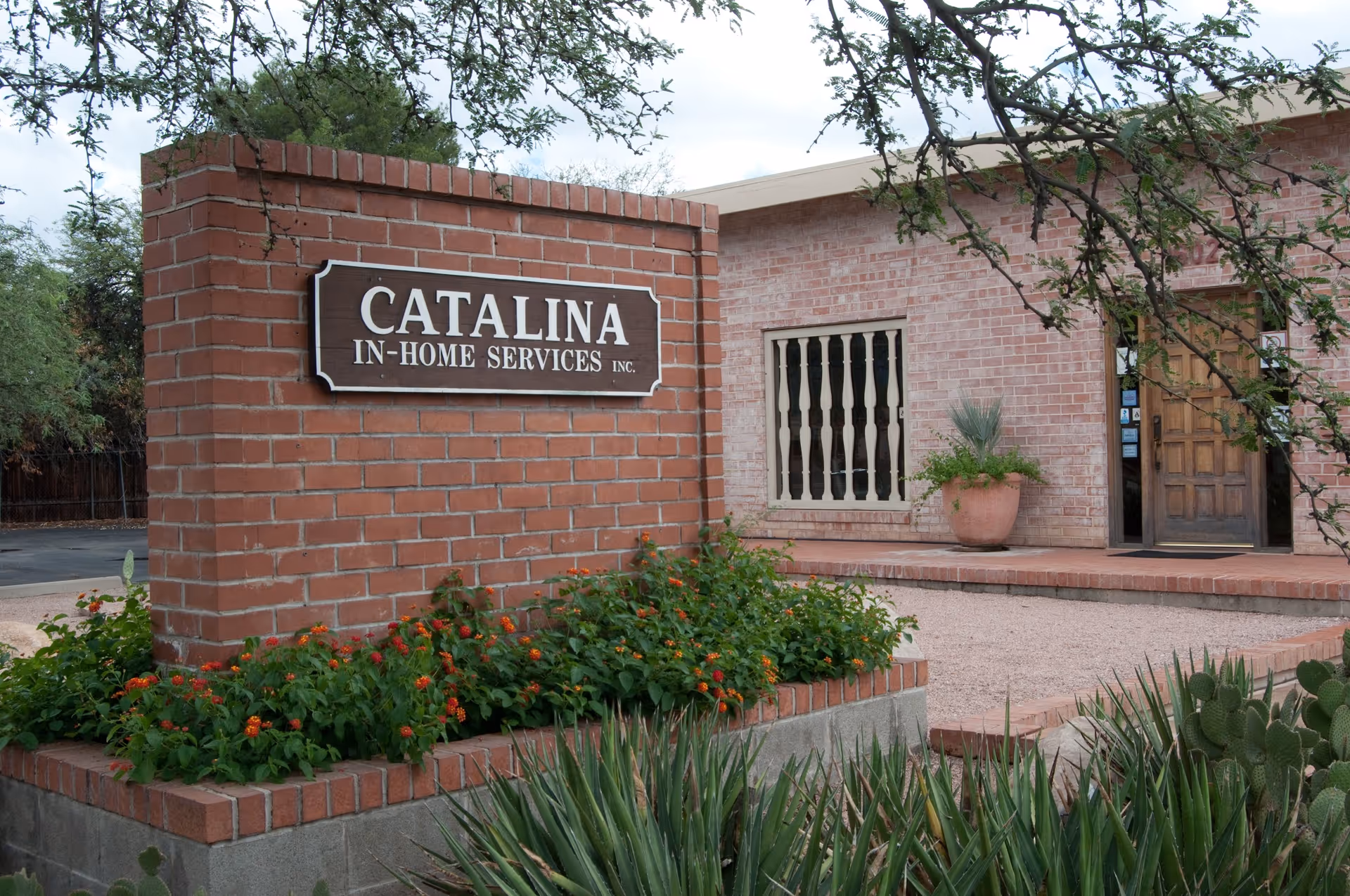 Red brick storefront with Catalina In-Home Services sign and landscaped front