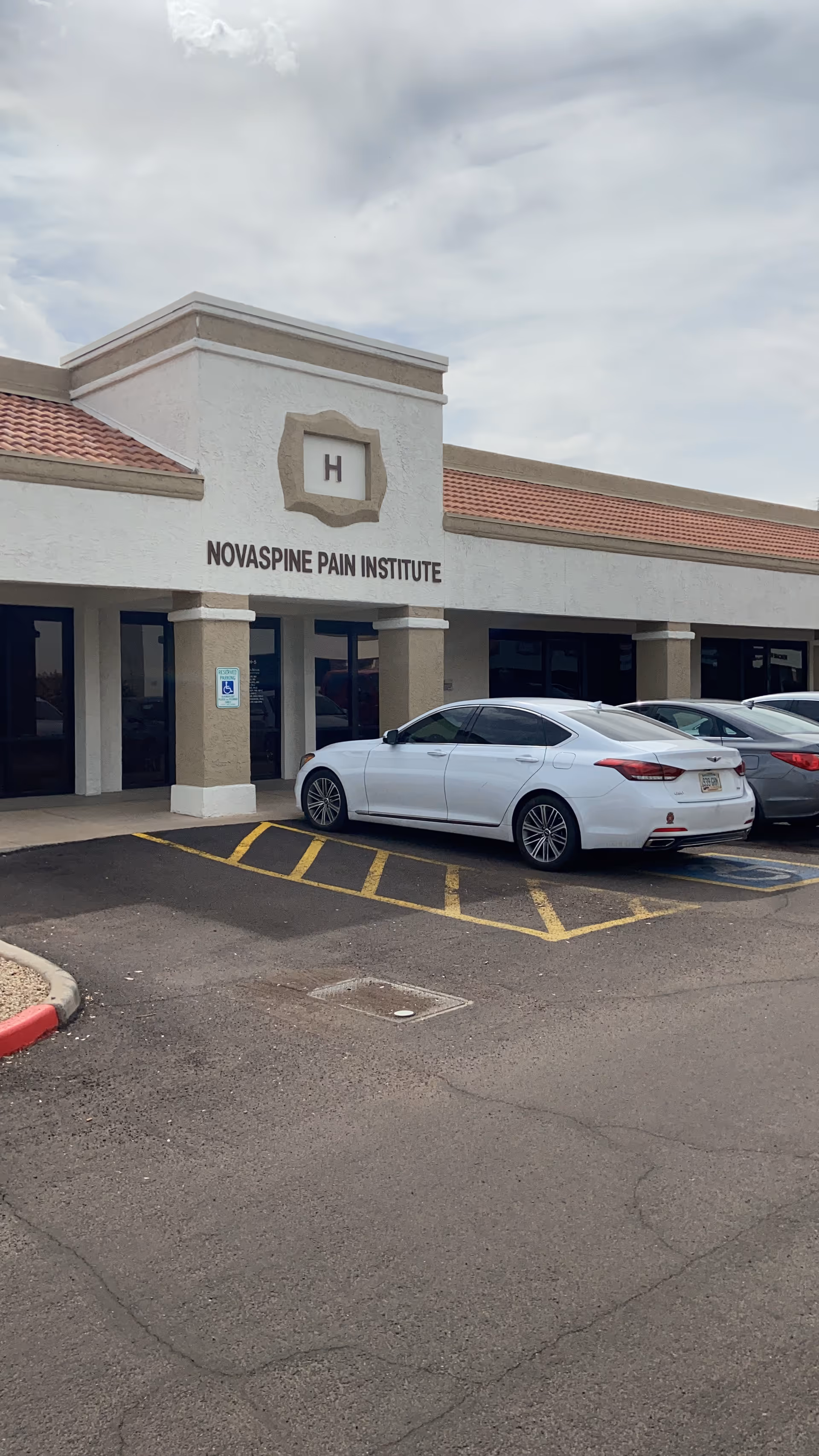 Front of a medical clinic building with signage and parked cars.