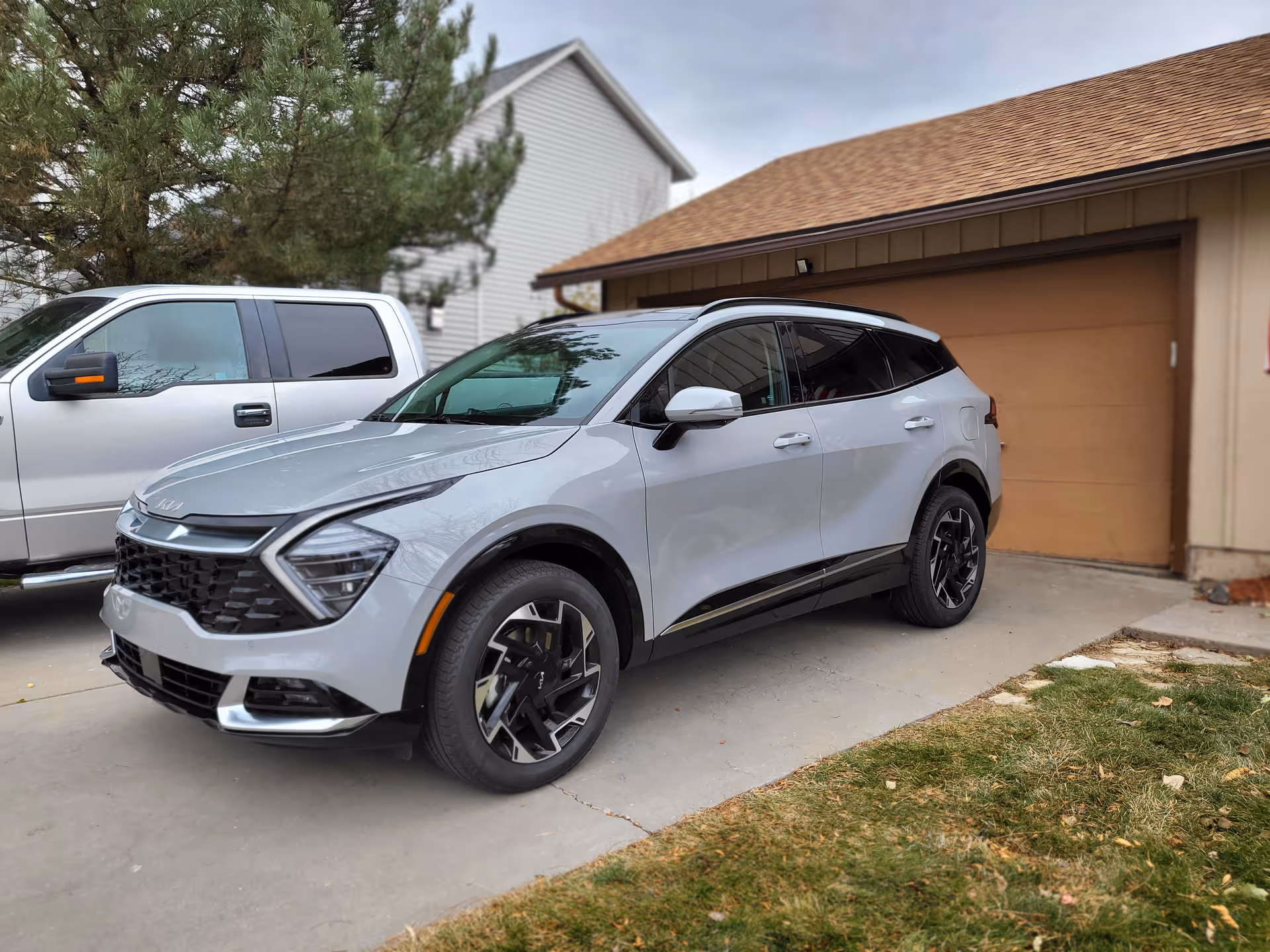 Silver SUV parked in a driveway beside a beige garage with brown door.