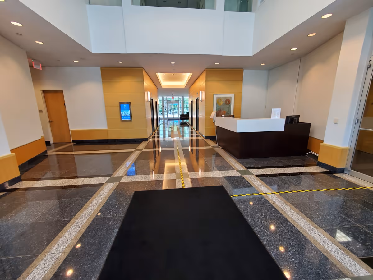 Bright interior lobby with a curved dark reception desk and polished marble floors.