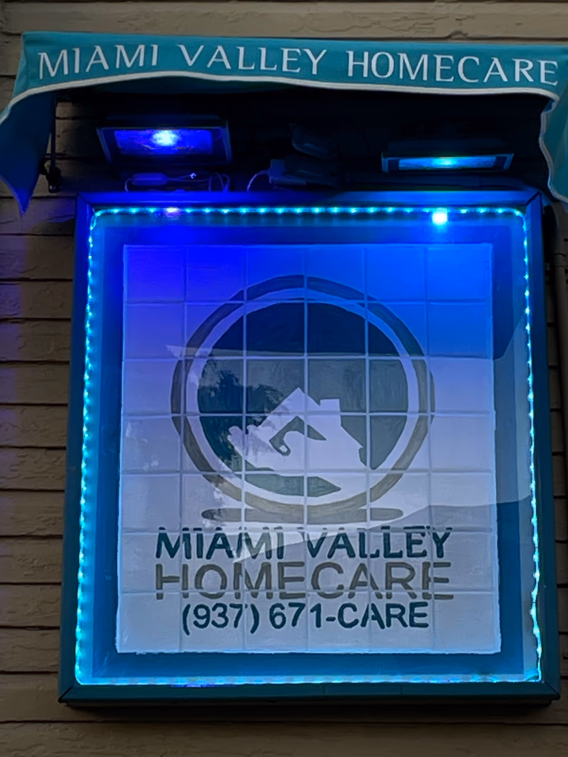 Exterior view of a Miami Valley Homecare sign with blue LED lights on a building.