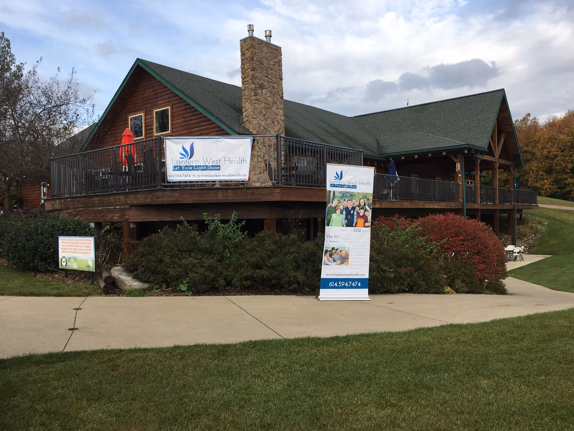 Rustic wooden lodge-style building with banners on a raised deck outside Lantern West Health.