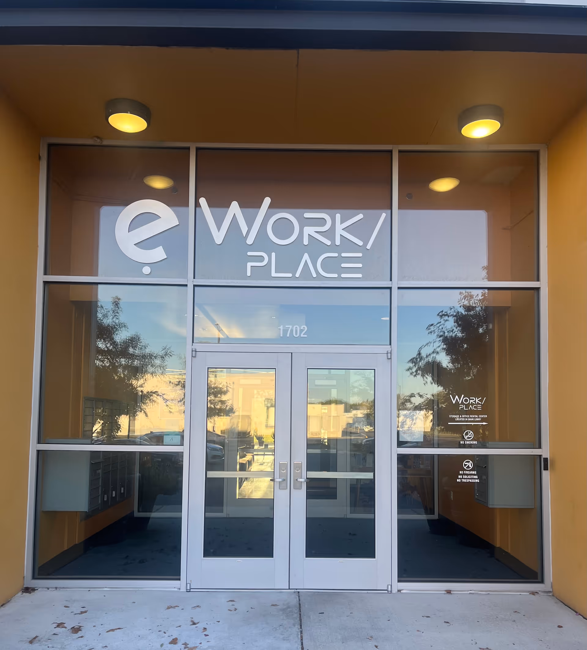 Glass double doors and large windows at a building entrance with a Work Place sign.