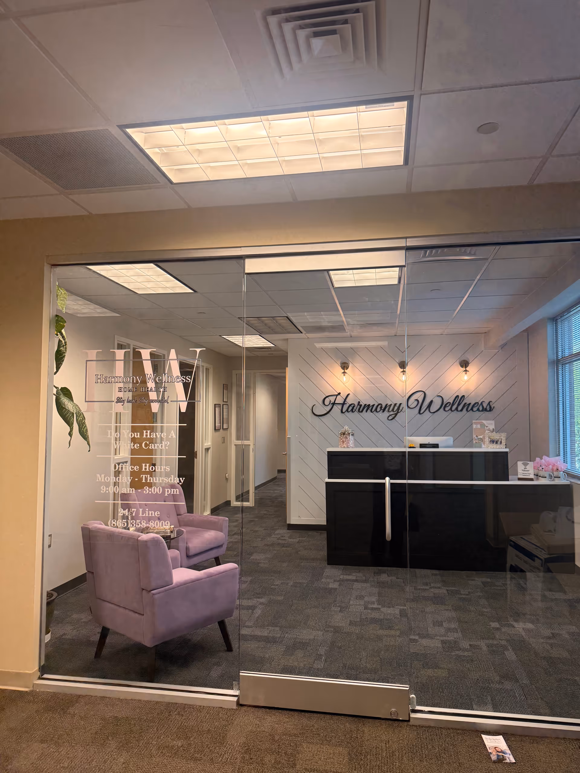 Reception lobby with glass doors, lavender chairs, and a Harmony Wellness sign