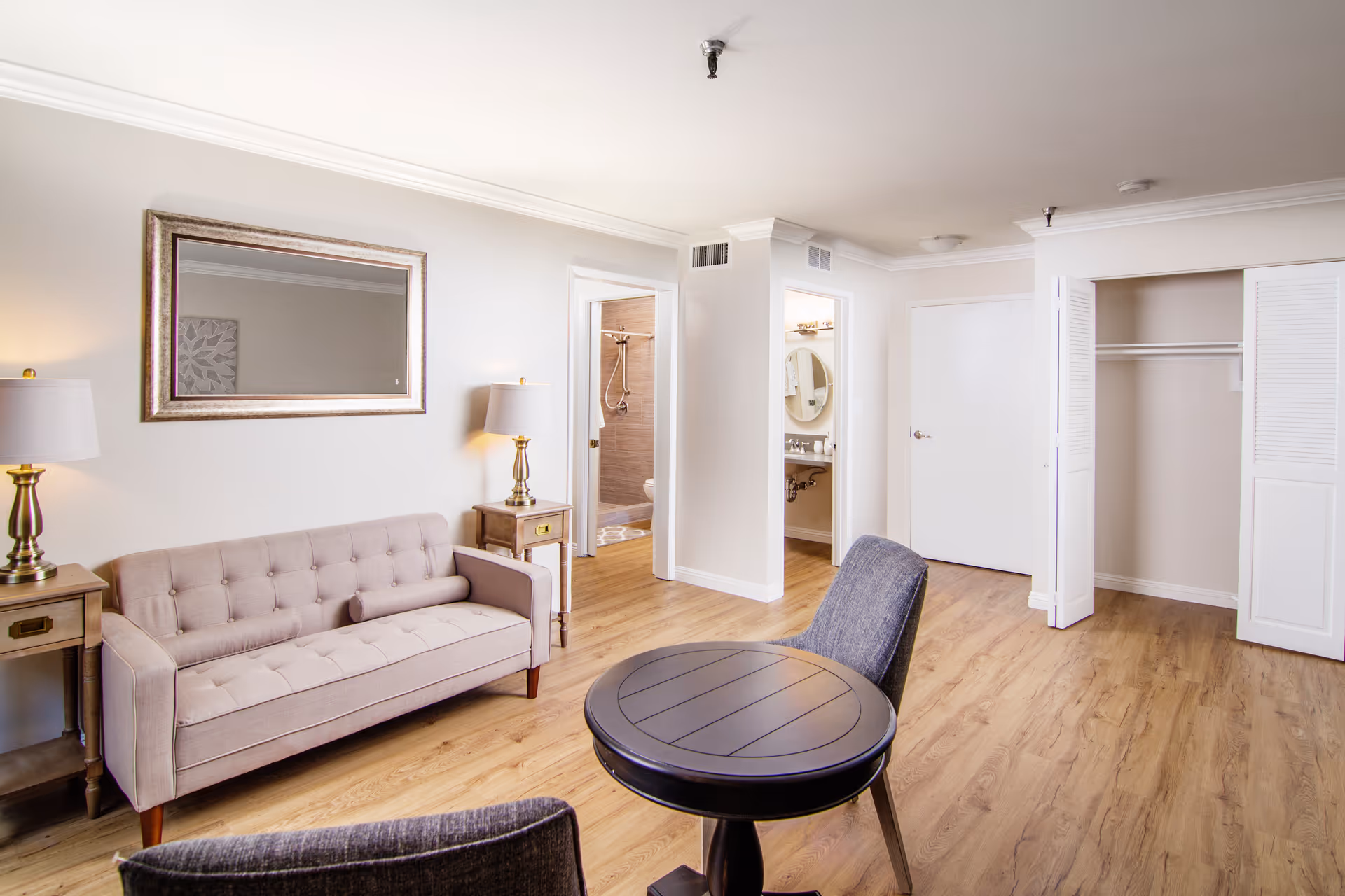 Bright living area featuring a beige tufted sofa, round table, and open closet doors.