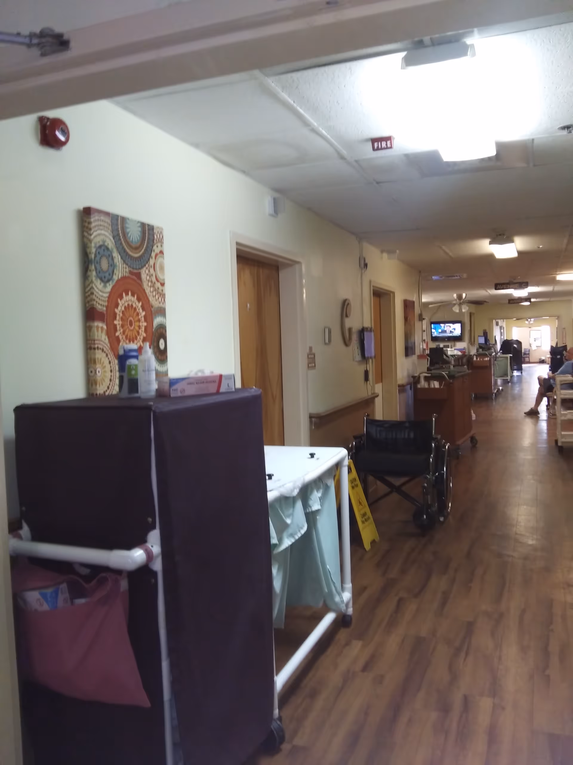 Long hallway in a senior living facility with wheelchairs and medical equipment.
