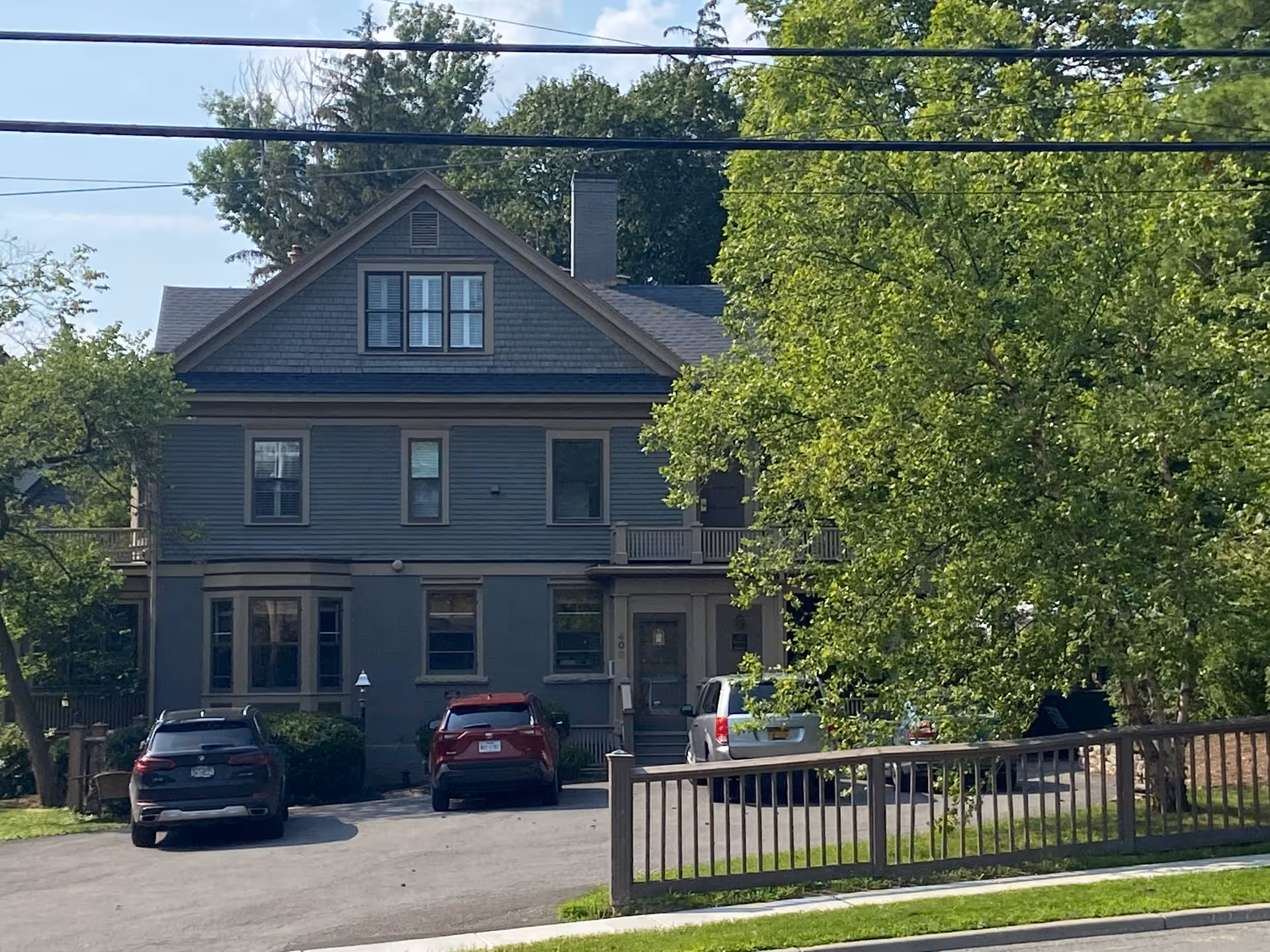 Exterior view of a Tudor-style senior living facility with cars and trees.