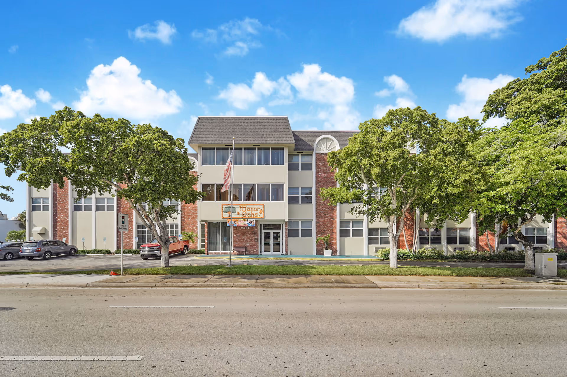 Exterior of a three-story retirement facility with brick accents and trees along the sidewalk.