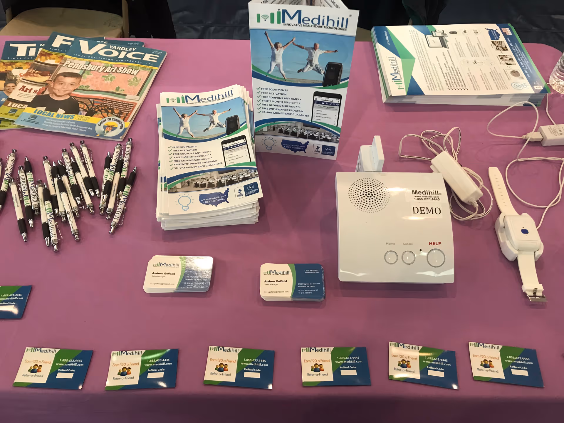 Indoor display table with Medihill brochures, pens, cards, and a demo unit.