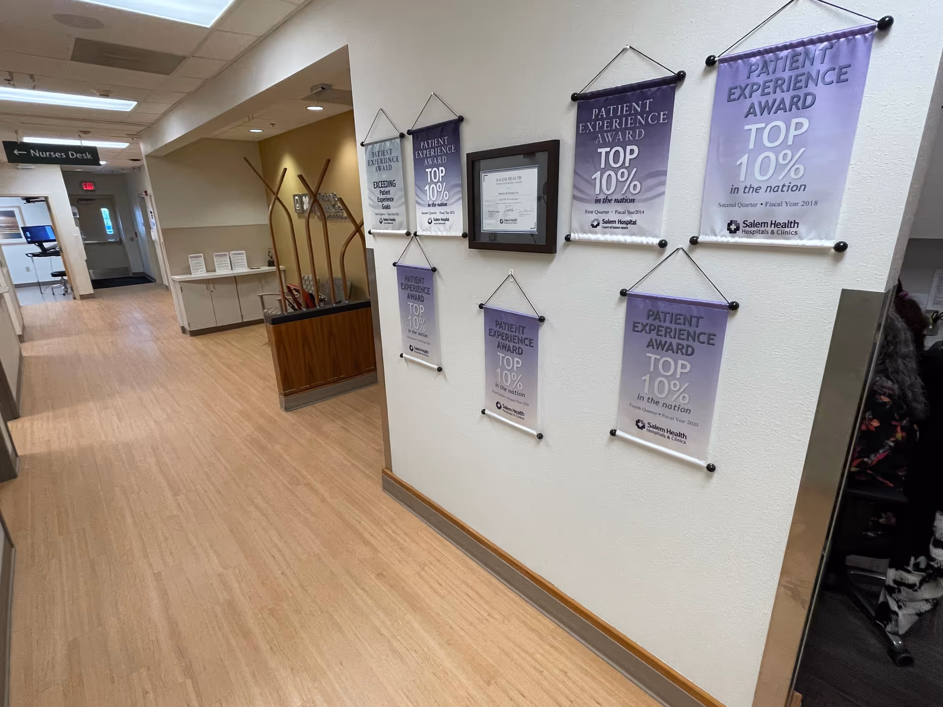 Interior hospital hallway with award banners and a nurse's desk in view