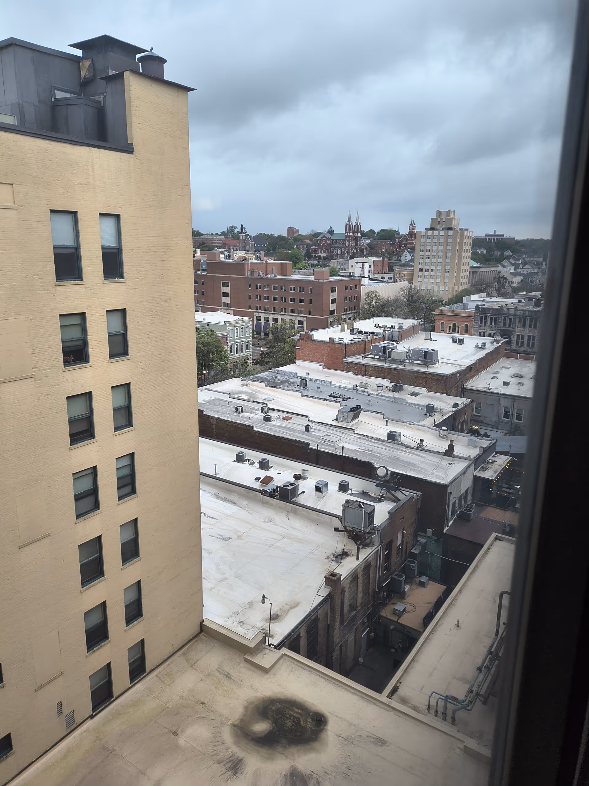View from Dempsey Apartments window: city rooftops and distant buildings.