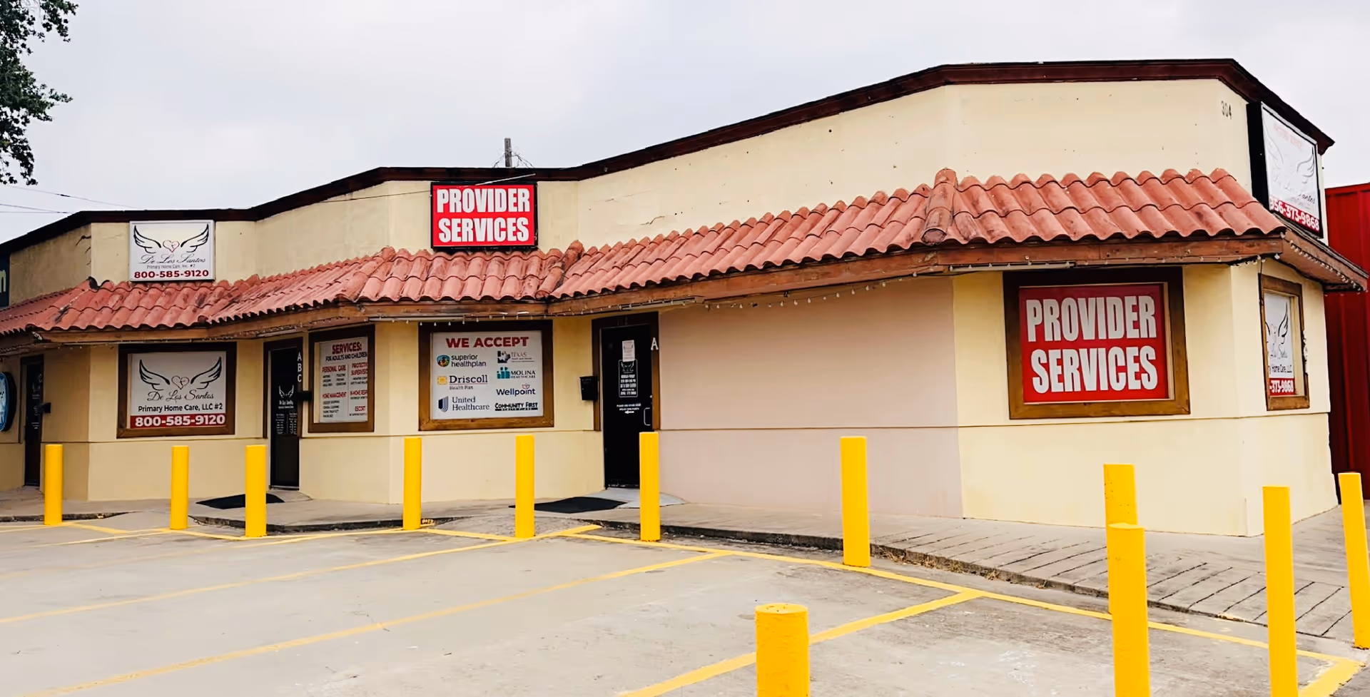 Beige single-story building with red-tiled roof, signage reading Provider Services, and yellow bollards.