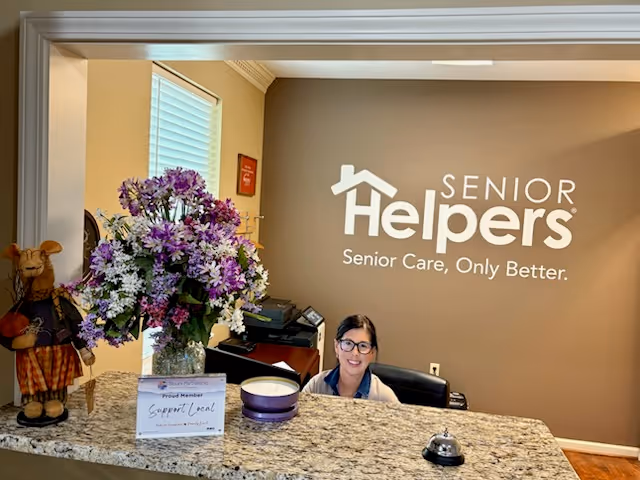 Reception area with a receptionist at a granite counter and a Senior Helpers sign