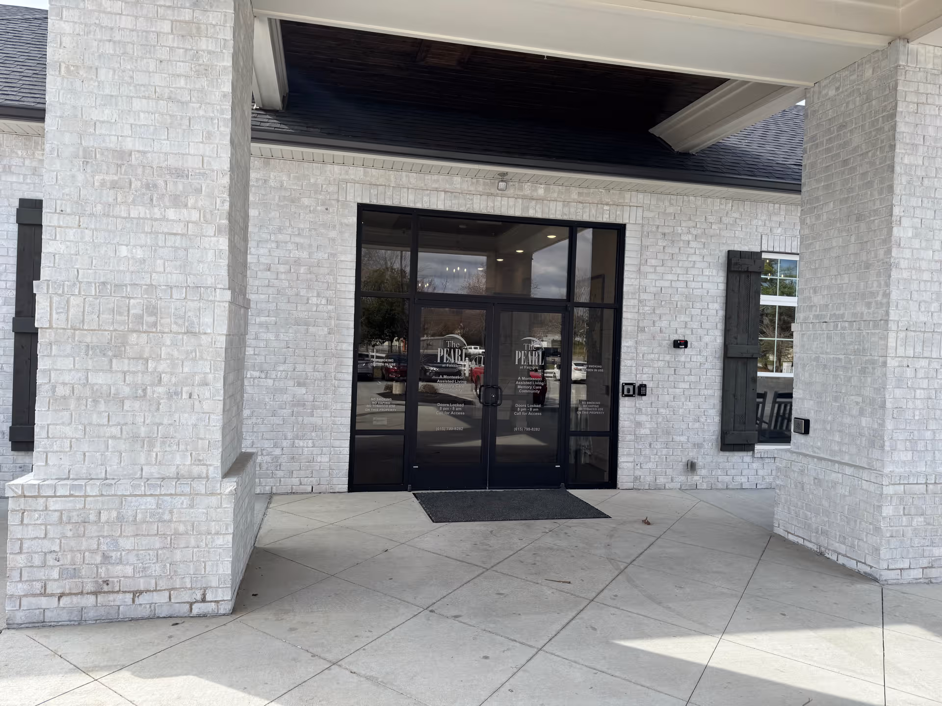 White brick building exterior with a glass double-door entrance labeled The Pearl at Fairview.