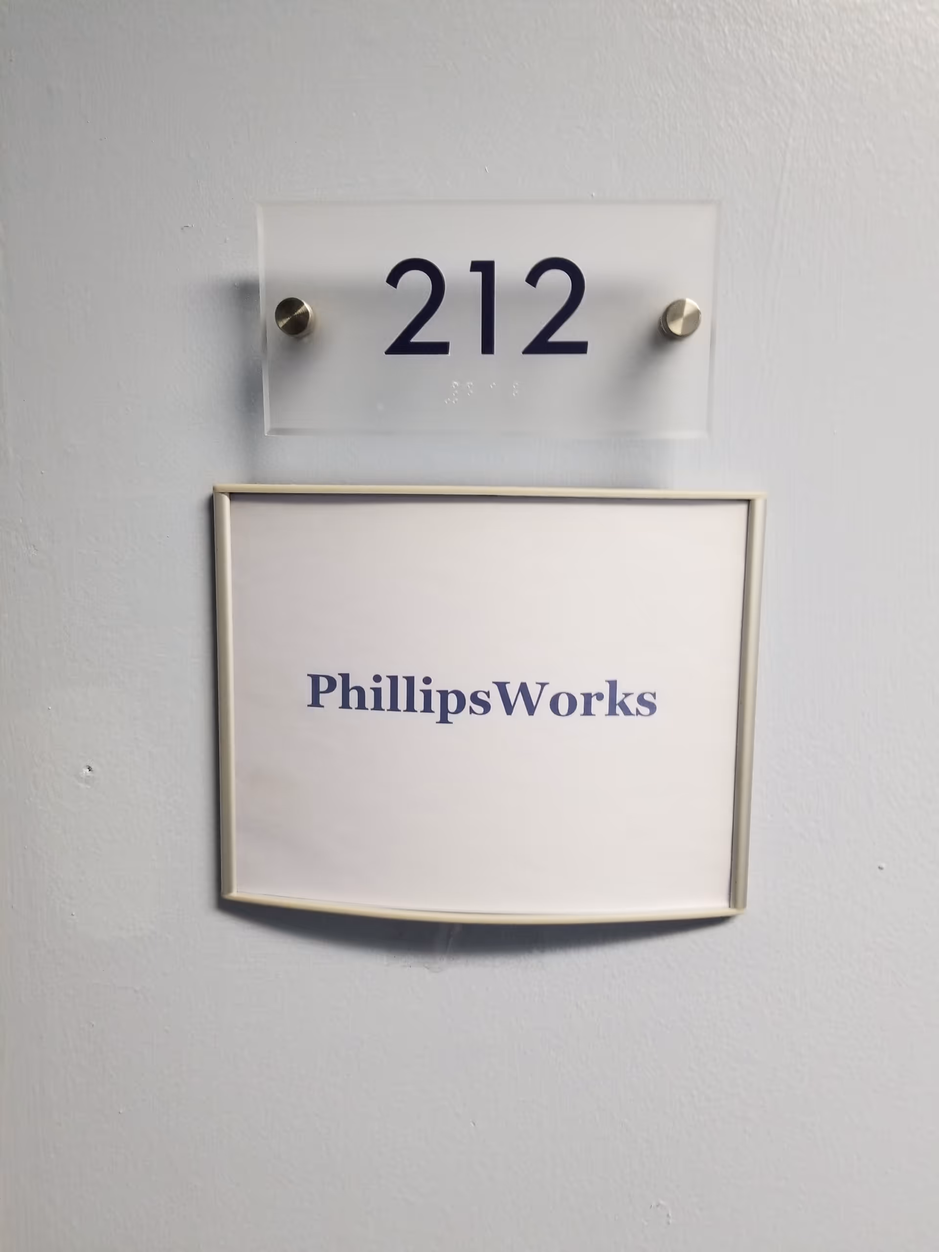 Interior wall with room 212 plaque and PhillipsWorks sign.