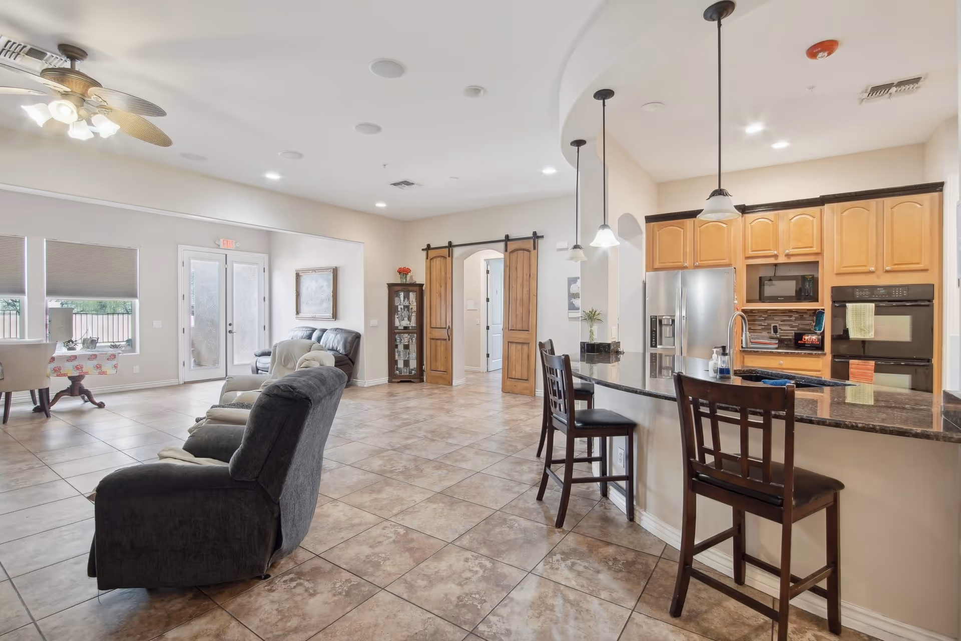 Open communal living area with tiled floor, lounge chairs, and a large kitchen island.