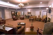 Spacious living room with multiple chairs, couches, tables, lamps, and a chandelier.