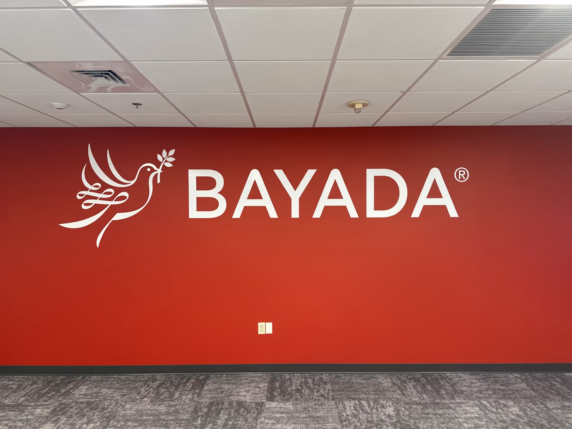 Red interior wall featuring the BAYADA logo and dove illustration.