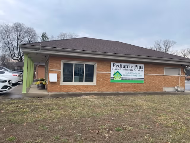 Brick single-story building with green trim and a Pediatric Plus sign in front.