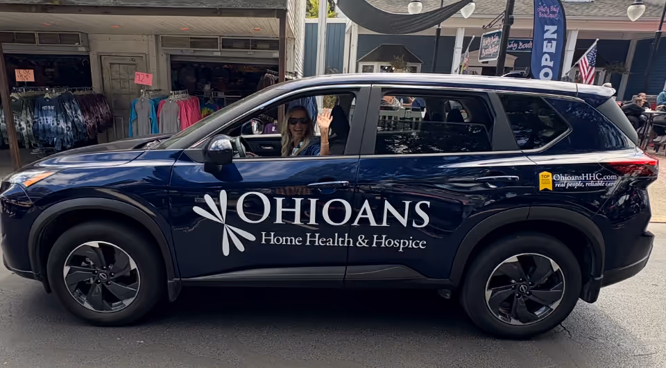 A dark blue SUV with Ohioans Home Health and Hospice branding parked on a city street.